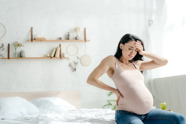 Schöne erschöpfte schwangere Mädchen mit Kopfschmerzen im Schlafzimmer — Stockfoto