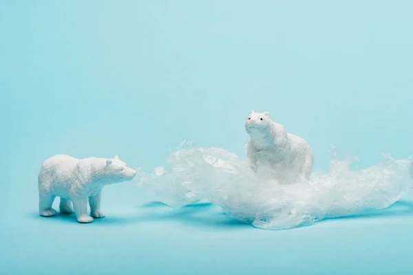 Toy polar bears with plastic packet on blue background, animal welfare concept — Stock Photo