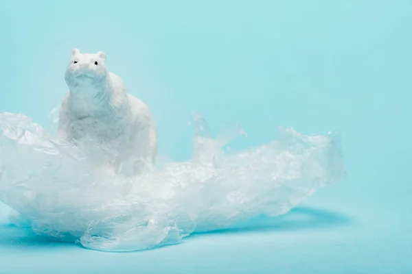 Spielzeug Eisbär auf Plastikverpackung auf blauem Hintergrund, Tierschutzkonzept — Stockfoto