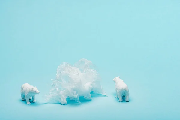 Toy polar bears with plastic packet on blue background, animal welfare concept — Stock Photo