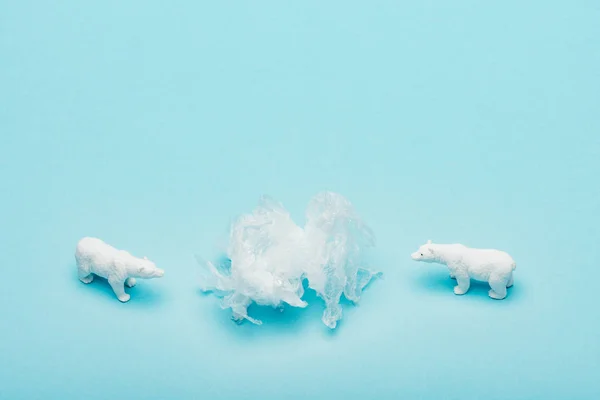 Osos polares de juguete con bolsa de polietileno sobre fondo azul, concepto de contaminación ambiental - foto de stock