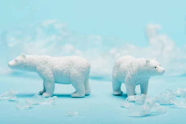 Dois ursos polares de brinquedo com lixo de polietileno no fundo azul, conceito de bem-estar animal — Fotografia de Stock