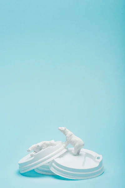Osos polares de juguete en tapas de café sobre fondo azul, concepto de bienestar animal - foto de stock