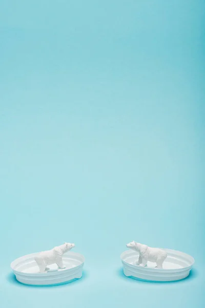 Dos osos polares de juguete en tapas de café sobre fondo azul con espacio para copias, concepto de bienestar animal - foto de stock