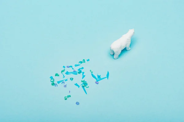 Vista ad alto angolo di giocattolo orso polare e pezzi di plastica su sfondo blu, concetto di benessere degli animali — Foto stock