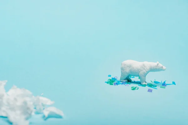 Selective focus of toy polar bear with polyethylene and plastic pieces on blue background, animal welfare concept — Stock Photo