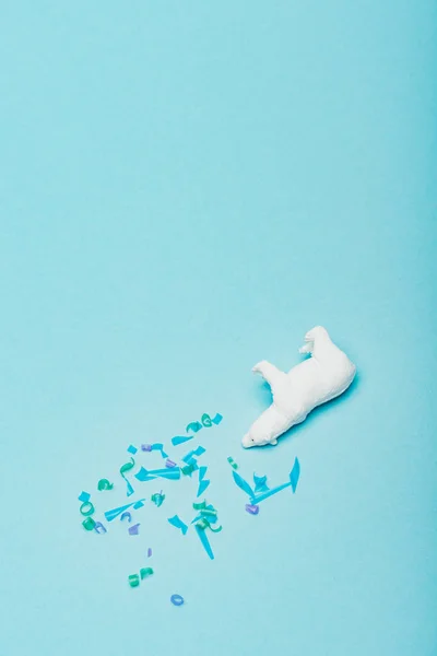 Top view of of toy polar bear with plastic pieces on blue background, animal welfare concept — Stock Photo