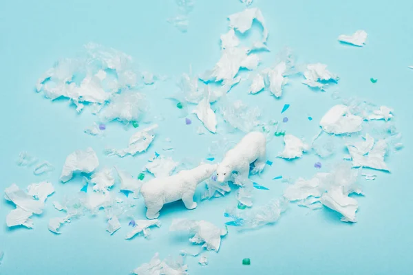 Toy polar bears with polyethylene and plastic pieces on blue background, environmental pollution concept — Stock Photo