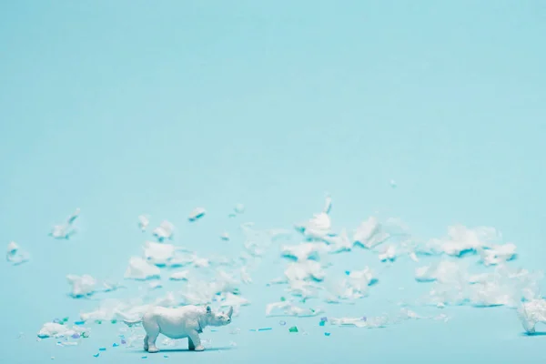 White rhinoceros toy and plastic garbage on blue background, environmental pollution concept — Stock Photo