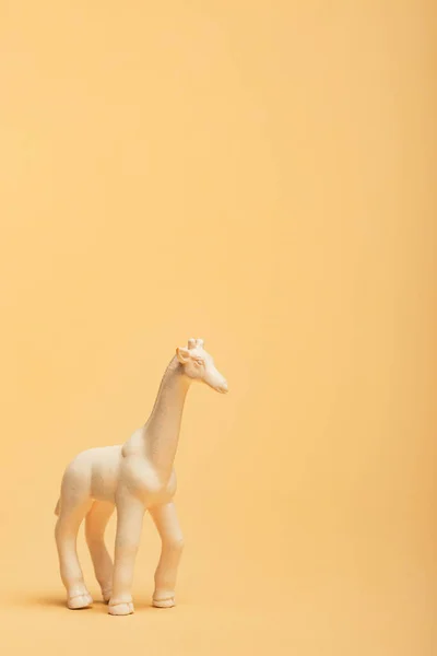 Jirafa de juguete blanco sobre fondo amarillo, concepto de bienestar animal - foto de stock