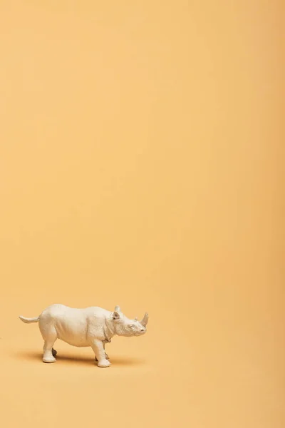 White toy rhinoceros on yellow background, animal welfare concept — Stock Photo