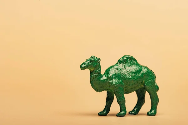 Green toy camel on yellow background, animal welfare concept — Stock Photo