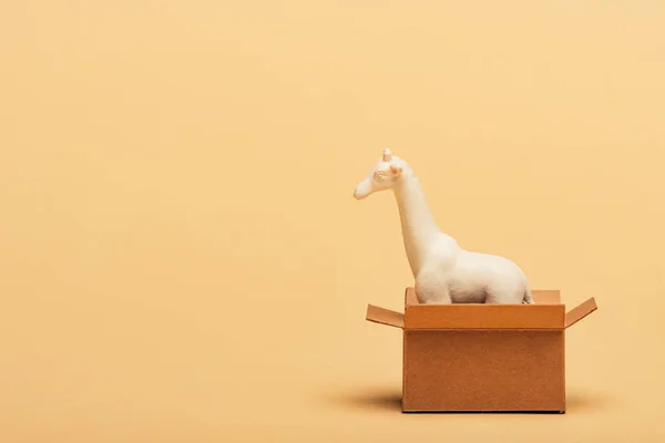 Girafa de brinquedo branco em caixa de papelão no fundo amarelo, conceito de bem-estar animal — Fotografia de Stock