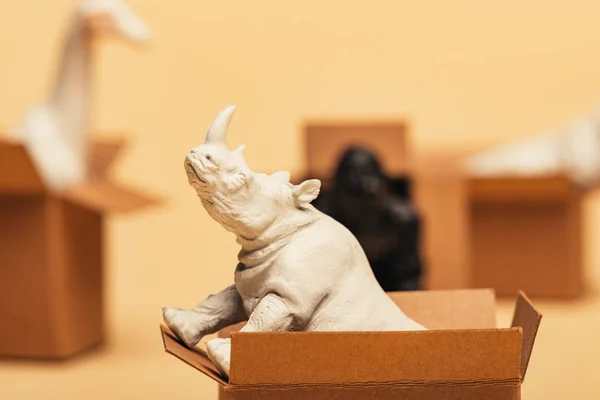 Focus selettivo di rinoceronti e animali giocattolo in scatole di cartone su sfondo giallo, concetto di benessere degli animali — Foto stock