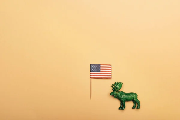 Vista superior de alce de juguete verde con bandera americana sobre fondo amarillo, concepto de bienestar animal - foto de stock