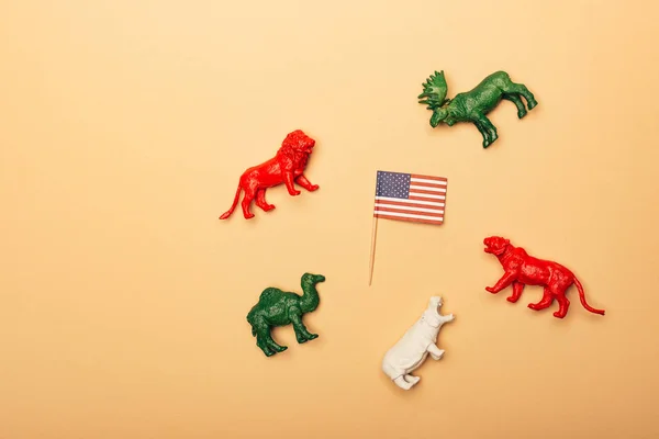 Vista superior de animales de juguete con bandera americana sobre fondo amarillo, concepto de bienestar animal - foto de stock