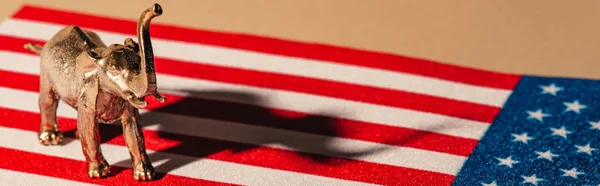 Colpo panoramico di elefante giocattolo dorato con ombra sulla bandiera americana, concetto di benessere animale — Foto stock