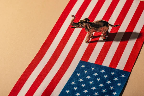 Elefante de juguete dorado con sombra en bandera americana, concepto de bienestar animal - foto de stock