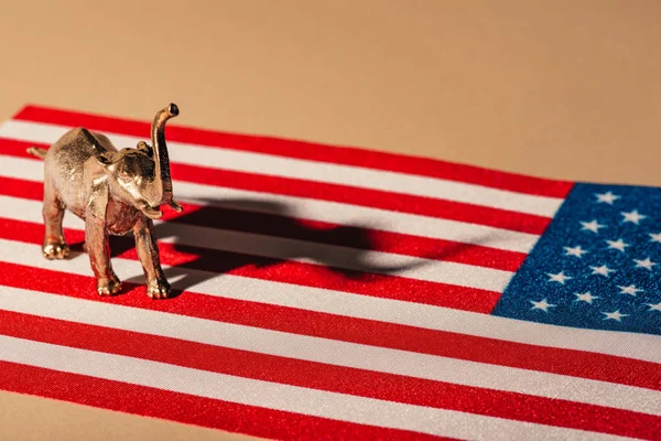 Elefante de juguete dorado con sombra en bandera americana, concepto de bienestar animal - foto de stock