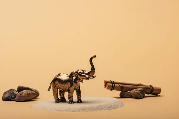 Jouet éléphant sur sable avec des pierres et des bâtons de bois sur fond jaune, concept de bien-être animal — Photo de stock