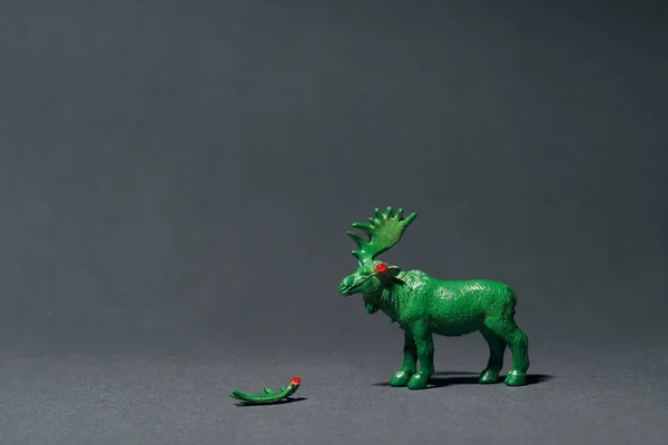 Green toy moose with horn on grey background, hunting for horns concept — Stock Photo