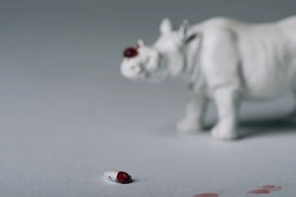 Enfoque selectivo de cuerno con sangre y rinoceronte de juguete sobre fondo gris, cazando concepto de cuerno - foto de stock