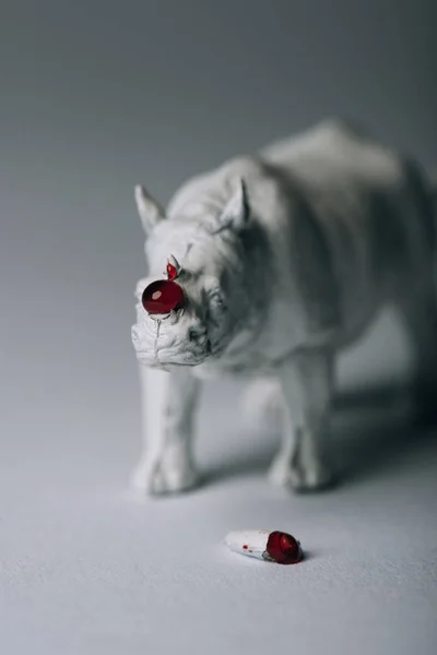 Corno con sangue e rinoceronte giocattolo su sfondo grigio, caccia al concetto di corno — Foto stock