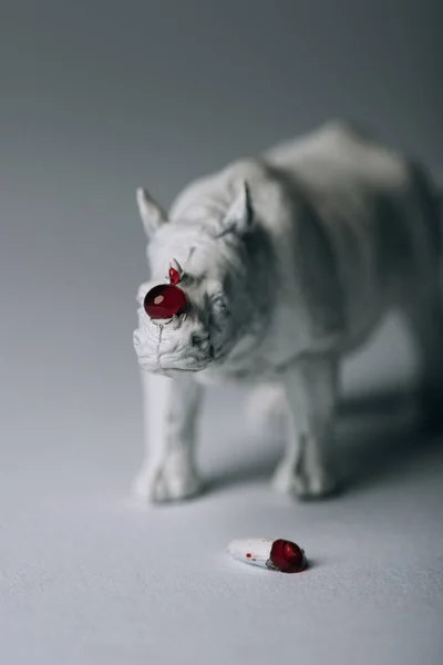 Corne avec du sang et rhinocéros jouet sur fond gris, chasse au concept de corne — Photo de stock