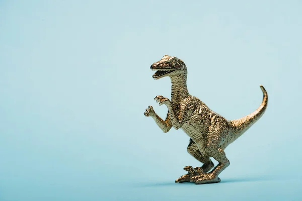 Dinosauro giocattolo dorato su sfondo blu con spazio di copia — Foto stock