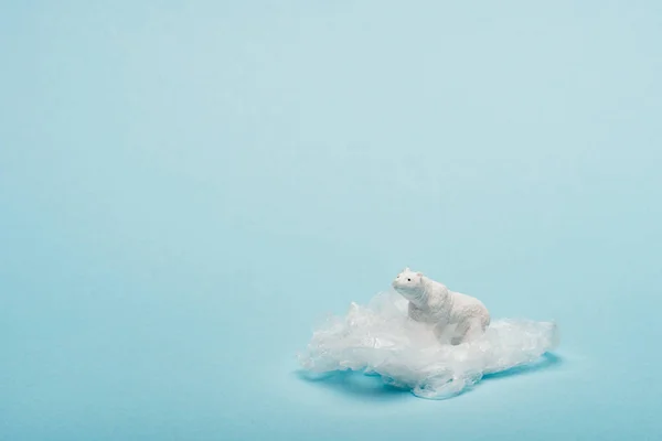 Toy polar bear on plastic packet on blue background, environmental pollution concept — Stock Photo