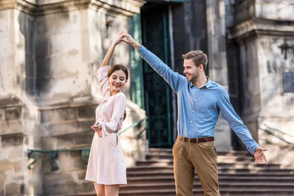 Couple of young, cheerful tourists dancing on street in sunlight — Stock Photo