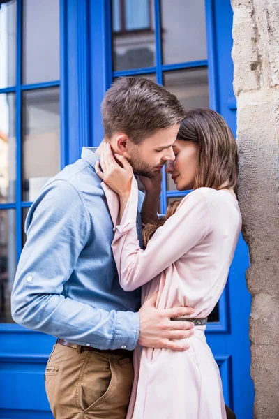 Young couple kissing on street while standing near blue door — Stock Photo
