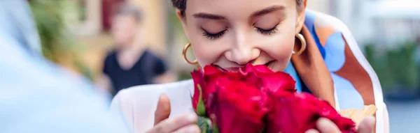 Vista ritagliata dell'uomo che presenta mazzo di rose alla fidanzata felice, colpo panoramico — Foto stock