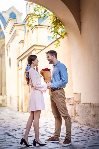 Junger Mann überreicht Rosenstrauß, während er Freundin auf der Straße einen Heiratsantrag macht — Stockfoto