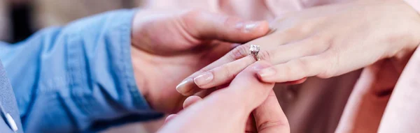 Vista recortada del hombre poniendo anillo de bodas en el dedo de la novia, tiro panorámico - foto de stock