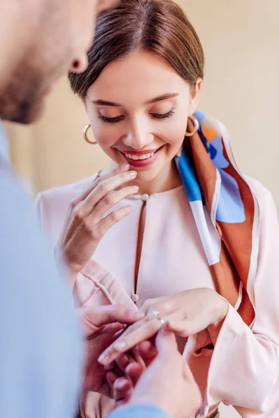 Cropped view of man putting wedding ring on finger of happy girlfriend — Stock Photo