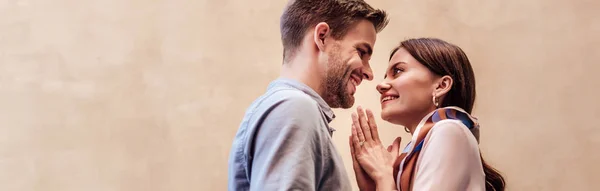 Tiro panorámico de mujer joven feliz mirando novio y mostrando por favor gesto - foto de stock
