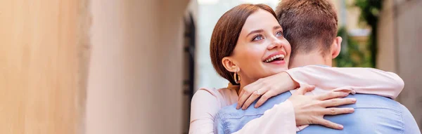Tiro panorámico de feliz joven mujer abrazando novio - foto de stock