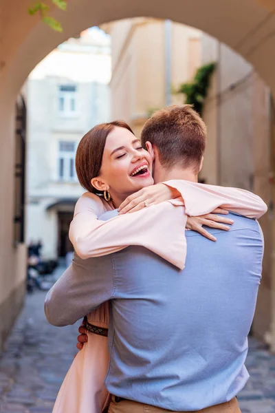 Happy young woman embracing boyfriend on street with closed eyes — Stock Photo