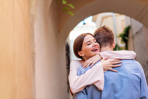 Feliz joven mujer abrazando novio en la calle con los ojos cerrados - foto de stock