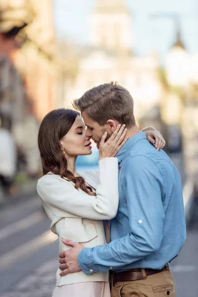 Приваблива молода жінка з закритими очима цілує красивого хлопця на вулиці — стокове фото