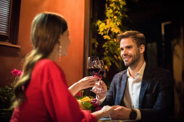 Happy man clinking glasses of red wine with girlfriend while making marriage proposal — Stock Photo