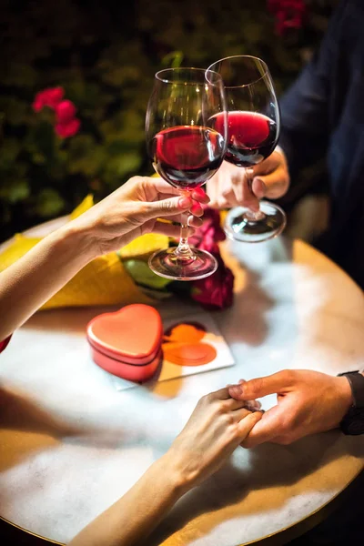 Vue recadrée de l'homme cliquetis verres de vin rouge avec petite amie tout en faisant la demande en mariage — Photo de stock