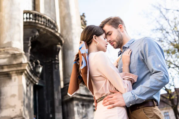 Feliz, joven pareja de turistas abrazando con los ojos cerrados en la calle - foto de stock