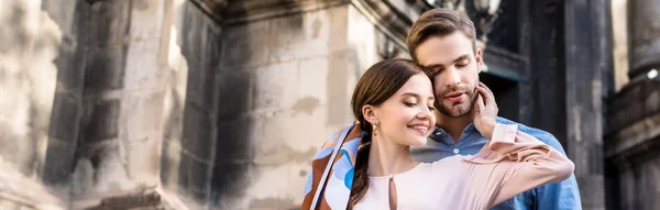 Панорамний знімок щасливої пари обіймається, стоячи на вулиці — стокове фото