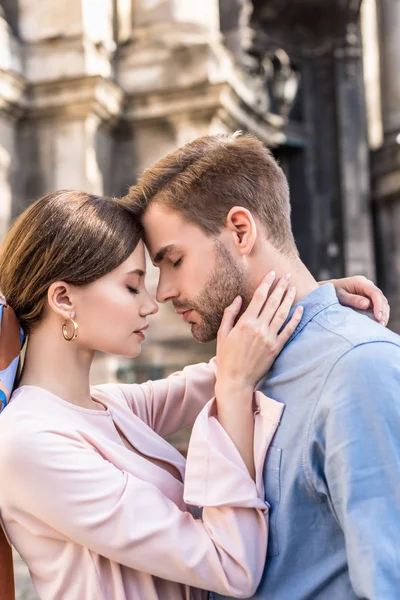 Young couple of tourists embracing with closed eyes while standing on street — Stock Photo