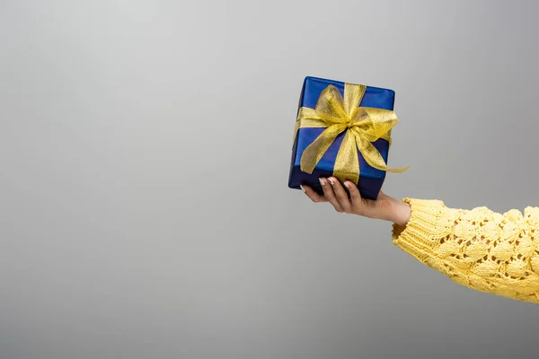 Cropped view of girl in yellow sweater holding present isolated on grey — Stock Photo