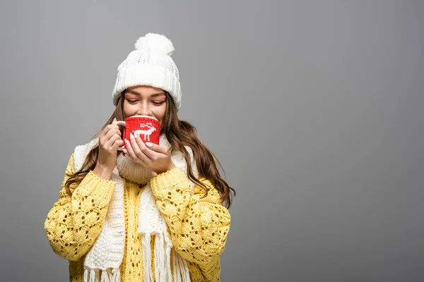 Fröhliches Mädchen in gelbem Pullover, Schal, Kakao trinkender Mütze auf grau — Stockfoto