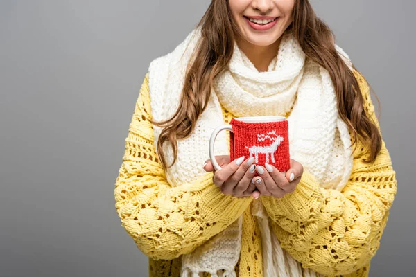 Vista recortada de chica feliz en suéter amarillo, bufanda sosteniendo taza de cacao aislado en gris - foto de stock