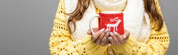 Vista recortada de chica en suéter amarillo, bufanda sosteniendo taza de cacao aislado en gris, tiro panorámico - foto de stock